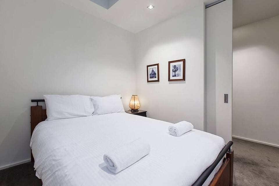 The main bedroom has a plush queen bed, built-in wardrobe, and a working corner furnished with a desk and chair