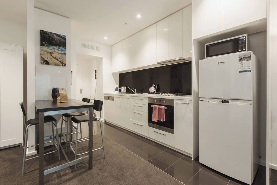 A contemporary and compact kitchen is fully-equipped with premium appliances including a gas stove, microwave, dishwasher, fridge and all the essential utensils