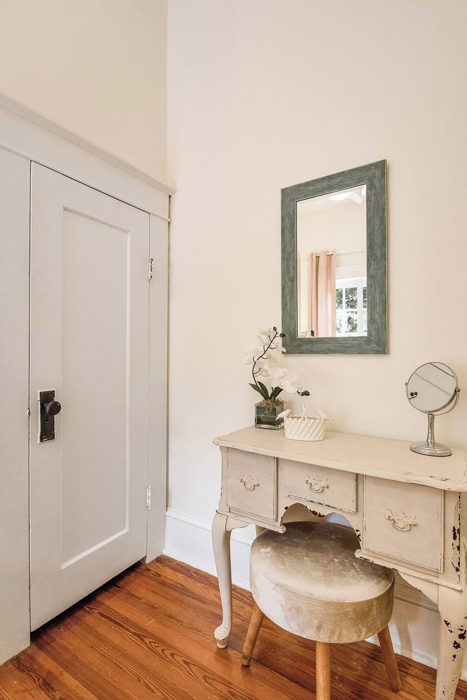 A petite vanity table, stool & mirror are provided