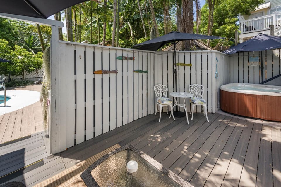 Private fenced deck with loveseat, light, spa, table and chairs with umbrellas