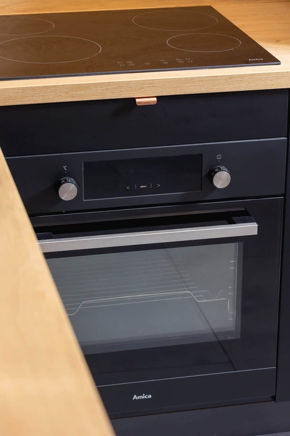 A close-up of a built-in oven with a wooden countertop above it.

