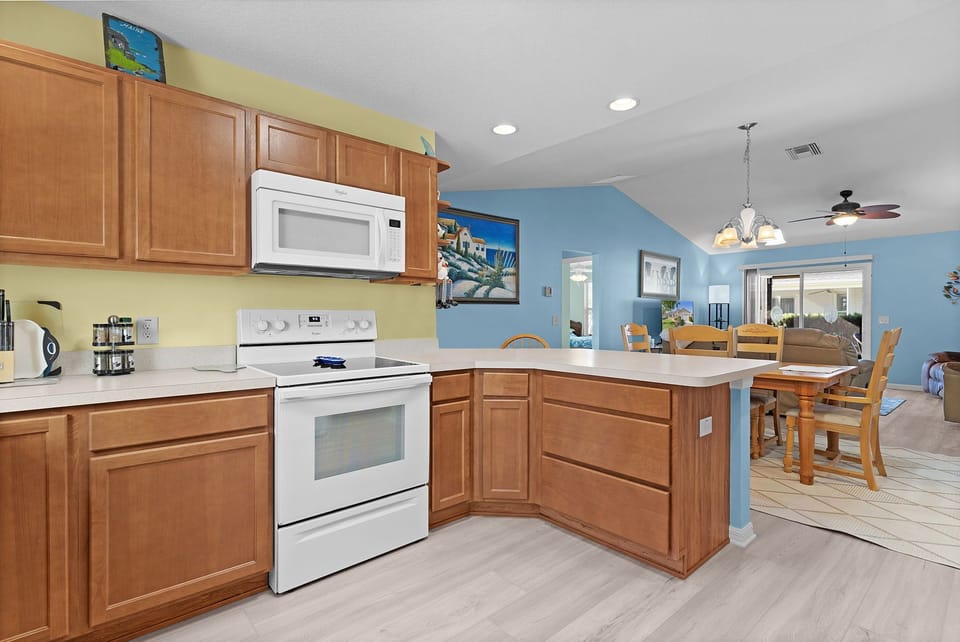 Step into your open-concept kitchen and dining space, featuring warm wood cabinetry, bright white countertops, and all the appliances you need to whip up memorable vacation meals together.