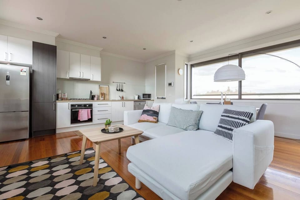 A bright second-floor living area features a comfortable L-shaped couch, sleek wooden coffee table and a flat-screen TV with Netflix
