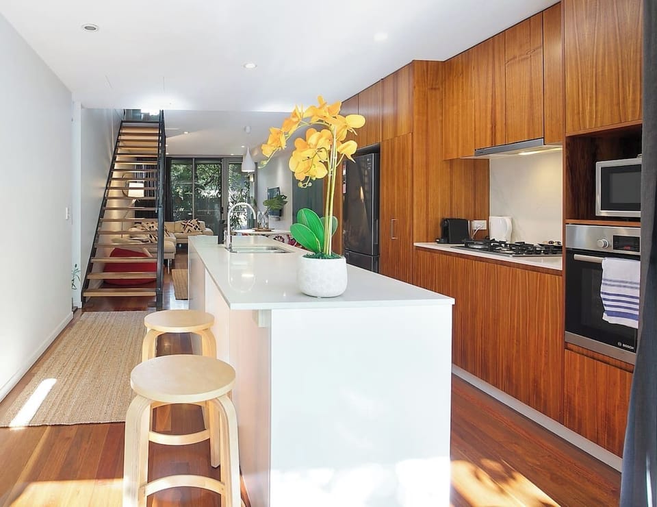 A sleek kitchen is designed around a breakfast bar and comes with contemporary appliances to cook a feast at home.