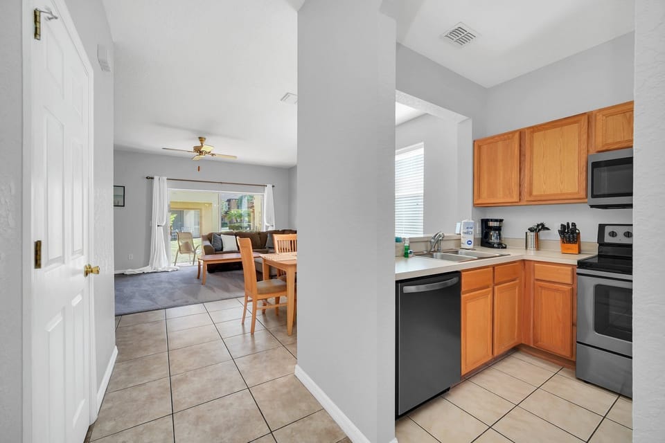 A kitchen sink area with warm cabinetry and modern appliances.