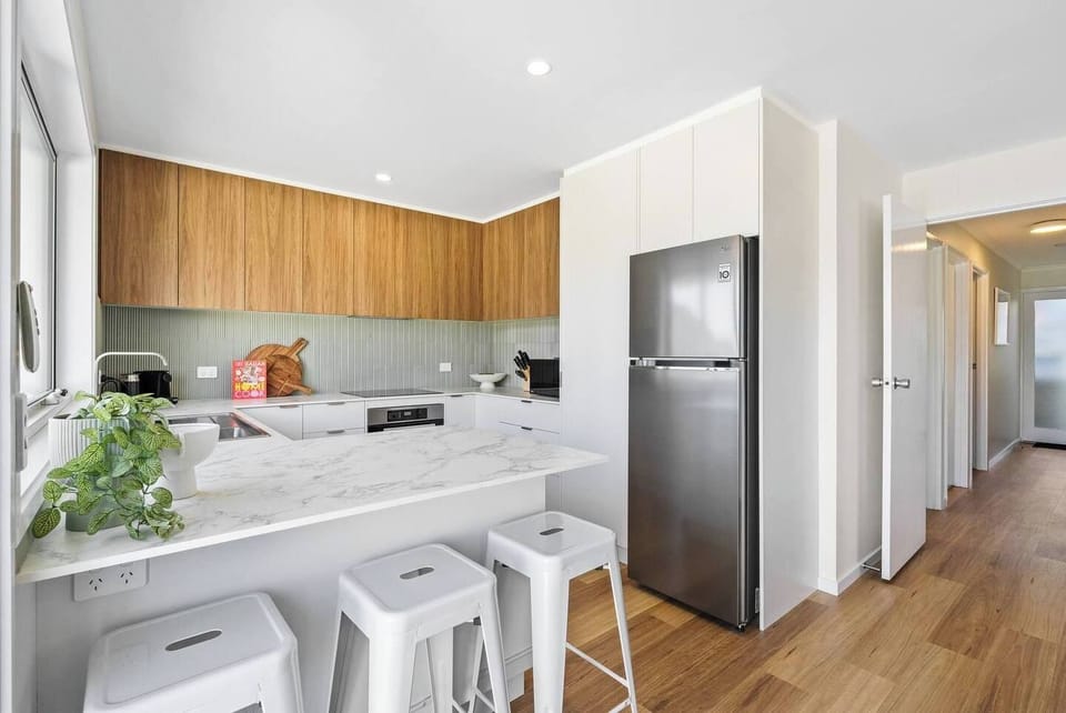 The kitchen features a ceramic cooktop, a dishwasher, and a breakfast bar that’s perfect for quick meals or evening cocktails. 