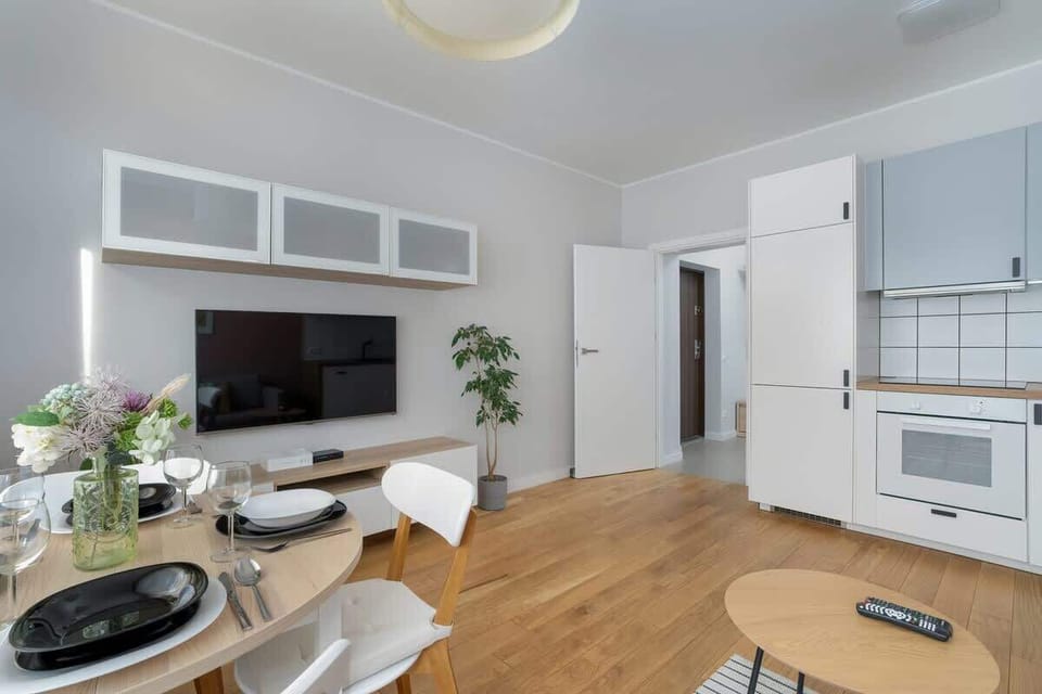A spacious living area with a TV, a round coffee table, and an open kitchen.

