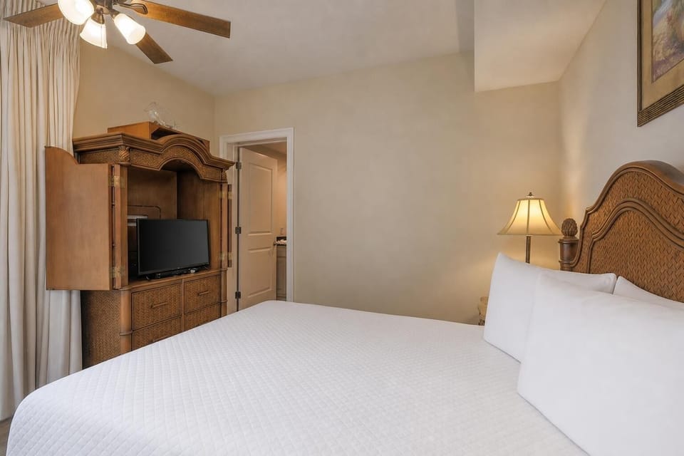 This cozy bedroom features a comfortable bed, a TV for entertainment, and warm wood accents, creating a relaxing retreat