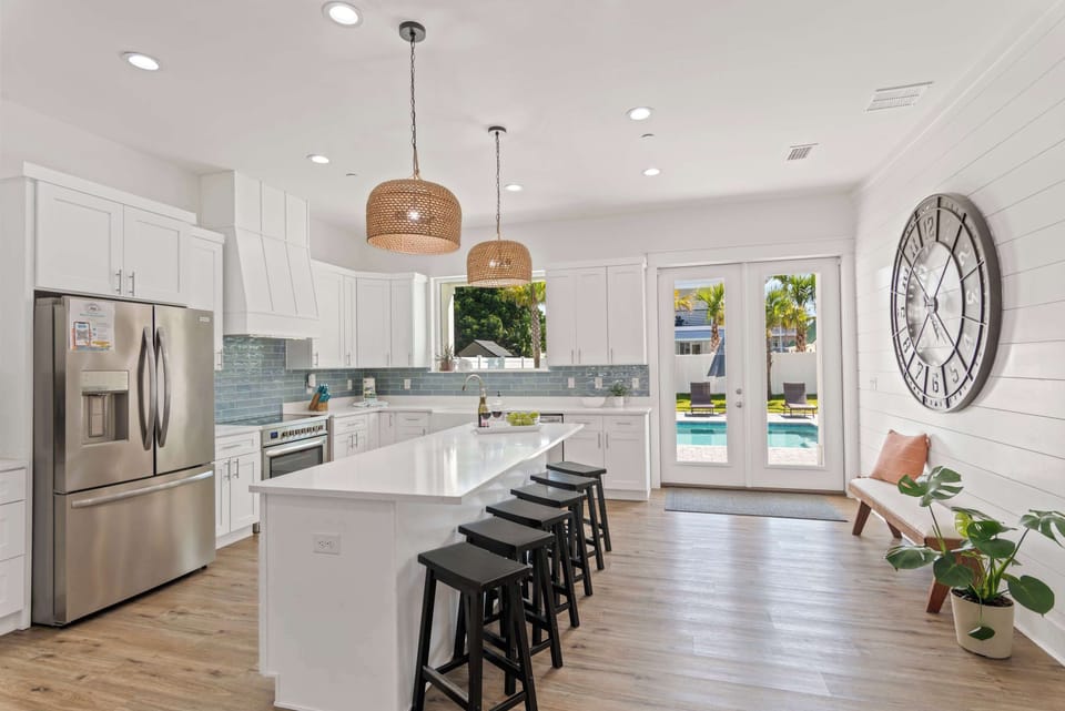Modern kitchen w/ island seating, sleek finishes, and warm natural light.