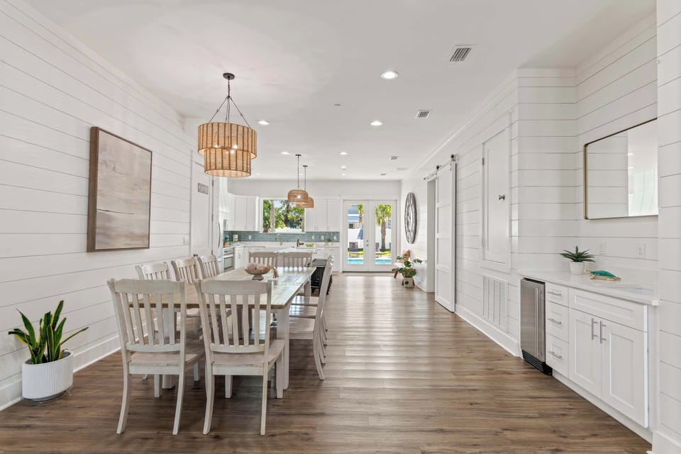 Dining room view w/ long table, pendant lights, and a bright open layout.