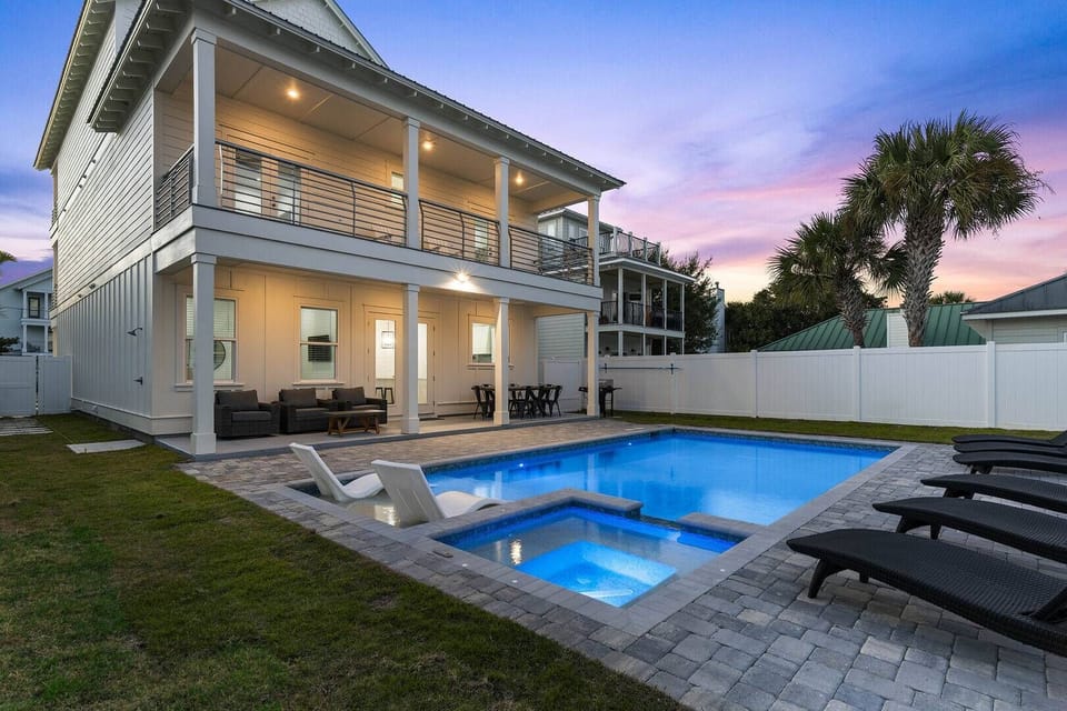 Evening pool view w/ glowing lights and a peaceful backyard atmosphere.