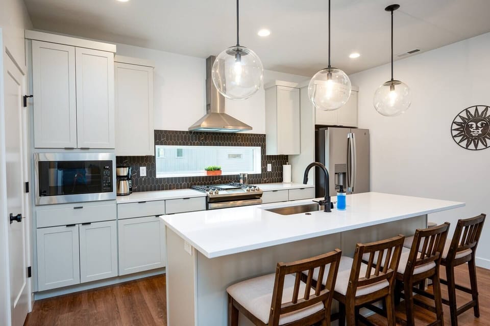 With its modern lighting, windows, quartz countertops, and stunning backsplash, the kitchen makes preparing dinner a truly enjoyable experience.