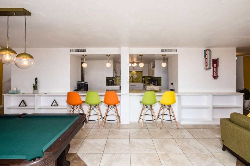 Entertainment area with barstools looking into kitchen.