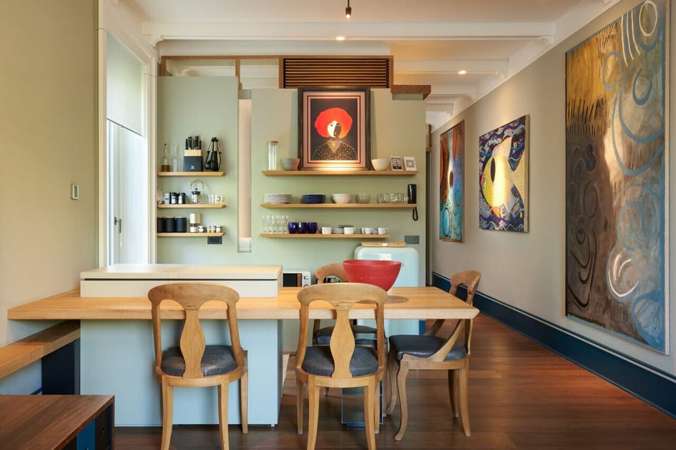 The open kitchen and dining area combine functionality with refined style, featuring artisanal decor, warm wood tones, and colorful contemporary art — perfect for enjoying meals in a creative, welcoming atmosphere.