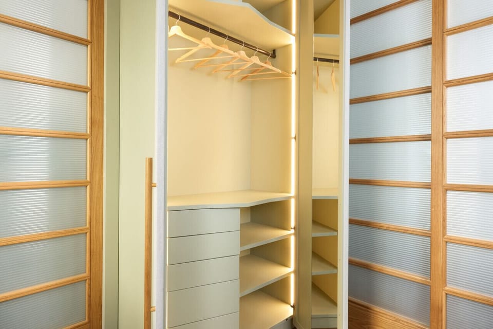 Spacious built-in wardrobe with internal lighting, open shelves, and drawers for optimal organization. Sliding shoji-style doors provide a refined, space-saving solution, blending functionality with minimalist design.
