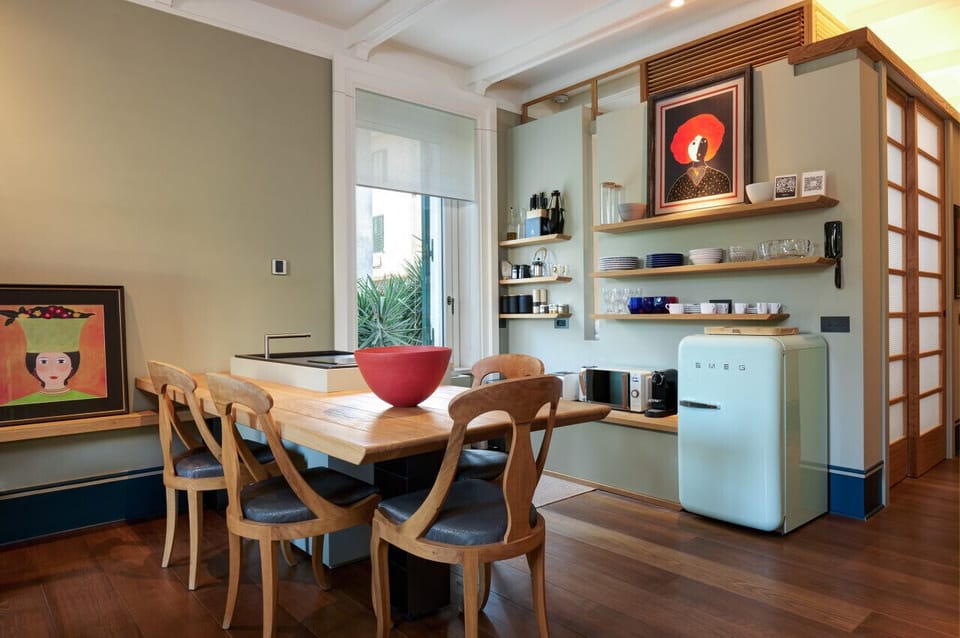 Bright and functional kitchen with vintage Smeg fridge, open shelves, and a solid wood dining table. The space blends mid-century charm with modern practicality, perfect for shared meals and relaxed mornings.