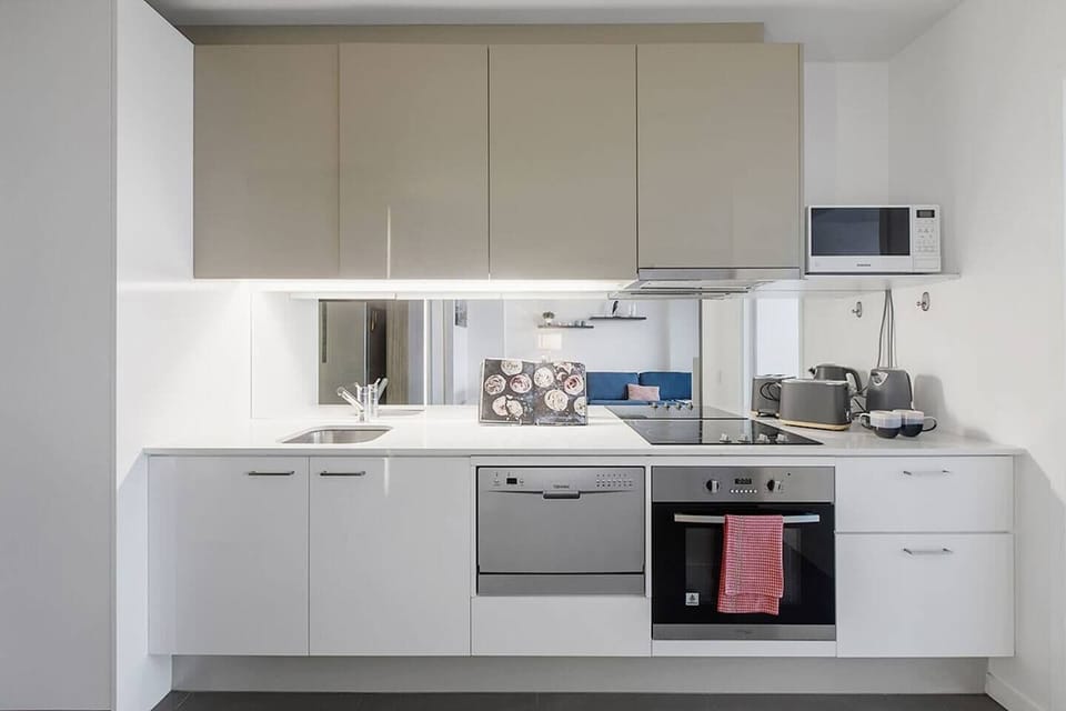 A sleek kitchen has Caesarstone surfaces and stainless-steel appliances including a dishwasher and an easy-clean induction cooktop
