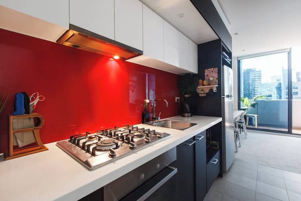 A contemporary kitchen features a quirky red splash-back and is fully equipped with modern appliances