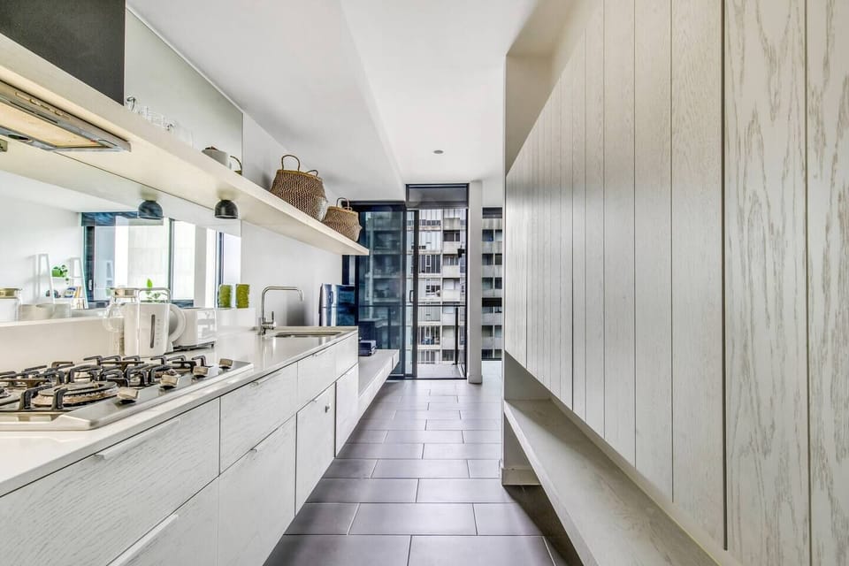 The galley-style kitchen comes fully equipped for meals at home with sleek appliances and utensils.

