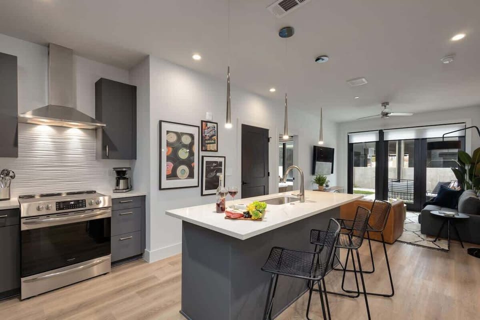 Fully equipped kitchen with stainless steel appliances, basic cooking essentials, toaster, coffee machine, and kitchen island seating.