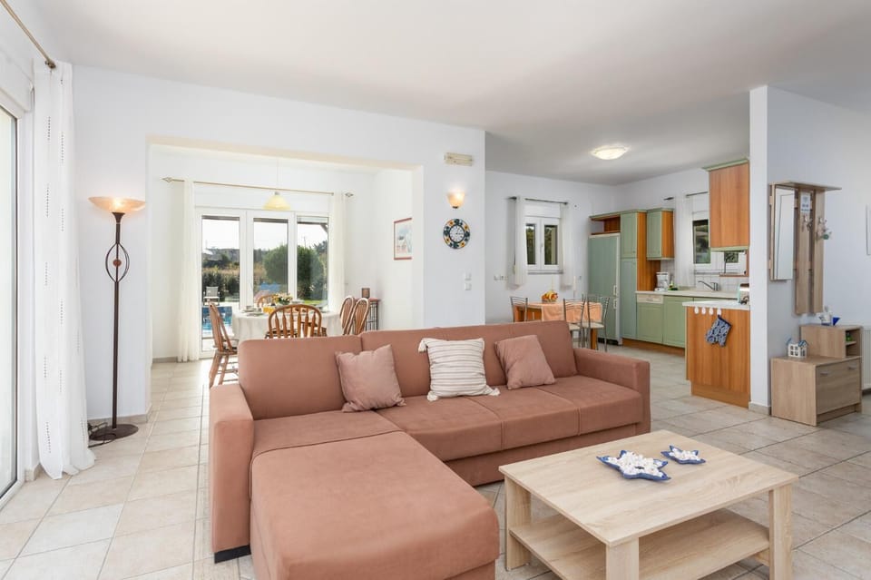 Open-plan living room with sofa, dining area, kitchen, ornamental fireplace, A/C, WiFi internet, and satellite TV