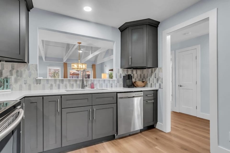 Your modern kitchen features sleek gray cabinets, stainless steel appliances, and a stylish backsplash—perfect for preparing meals during your stay.