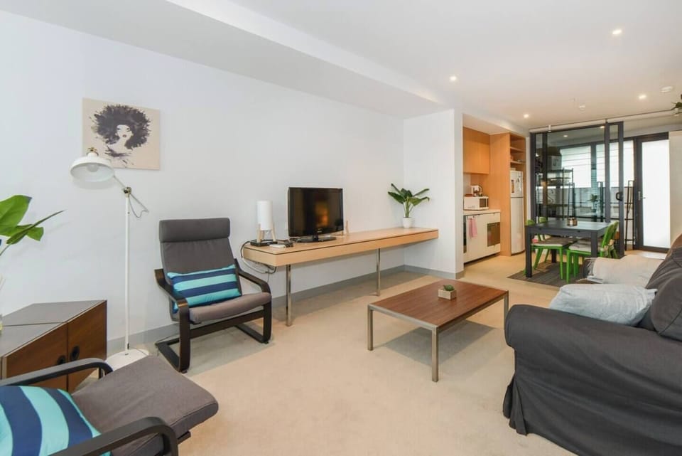 A bright and comfortable living area is furnished with a two-seater lounge, two additional armchairs and a TV