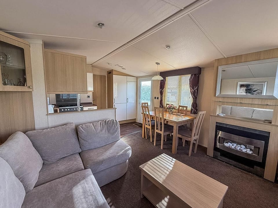 Unwind in the living area as the electric fireplace warms the room, creating the perfect atmosphere for a relaxing evening after a day of exploring the Suffolk coast.