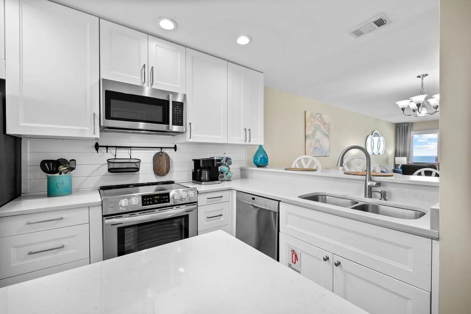 Modern white kitchen with stainless steel appliances and a breakfast bar.