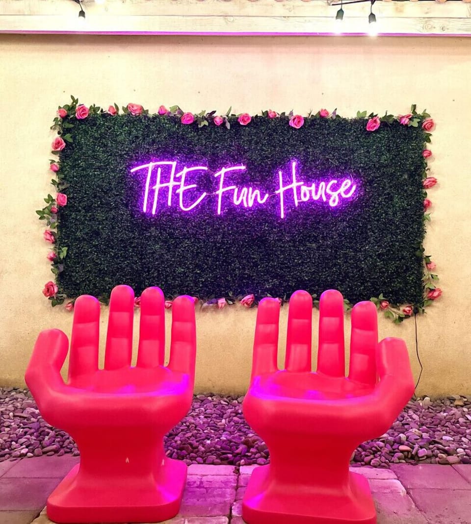 Snap a pic under the neon “The Fun House” sign w/ bold pink lounge chairs