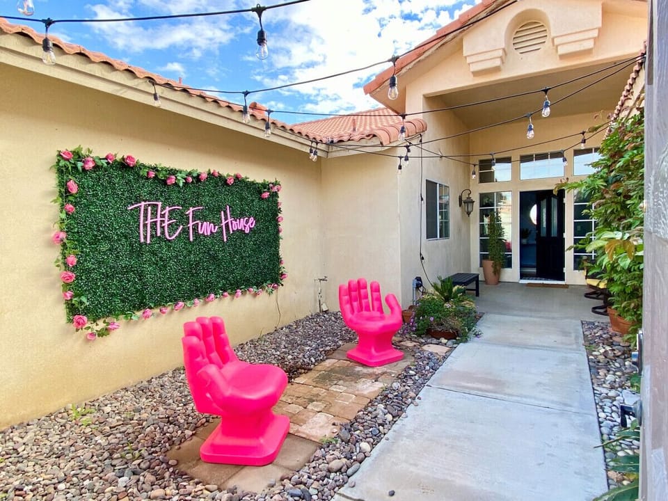 Cheerful entry courtyard w/ neon sign & bold pink lounge chairs
