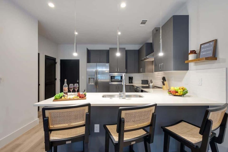 Fully equipped kitchen with stainless steel appliances, basic cooking essentials, toaster, coffee machine, and kitchen bar seating.