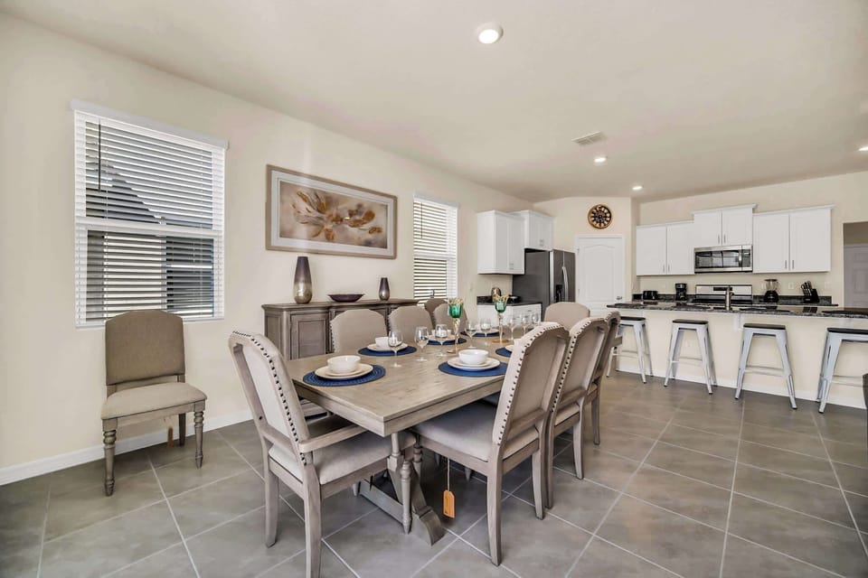 Spacious dining area with seating for eight, perfect for family gatherings, adjacent to a modern kitchen with a breakfast bar.