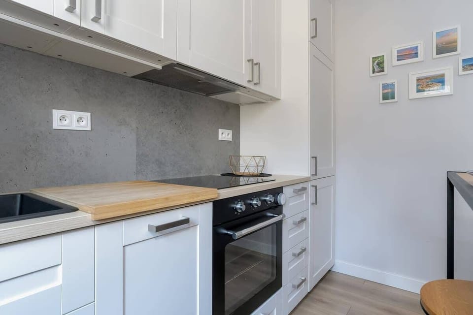 A partial view of the modern kitchen with a stovetop, white cabinets, and a neutral backsplash.






