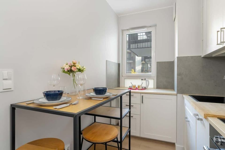 A small dining corner with a round table, chairs, and flowers next to the kitchen.
