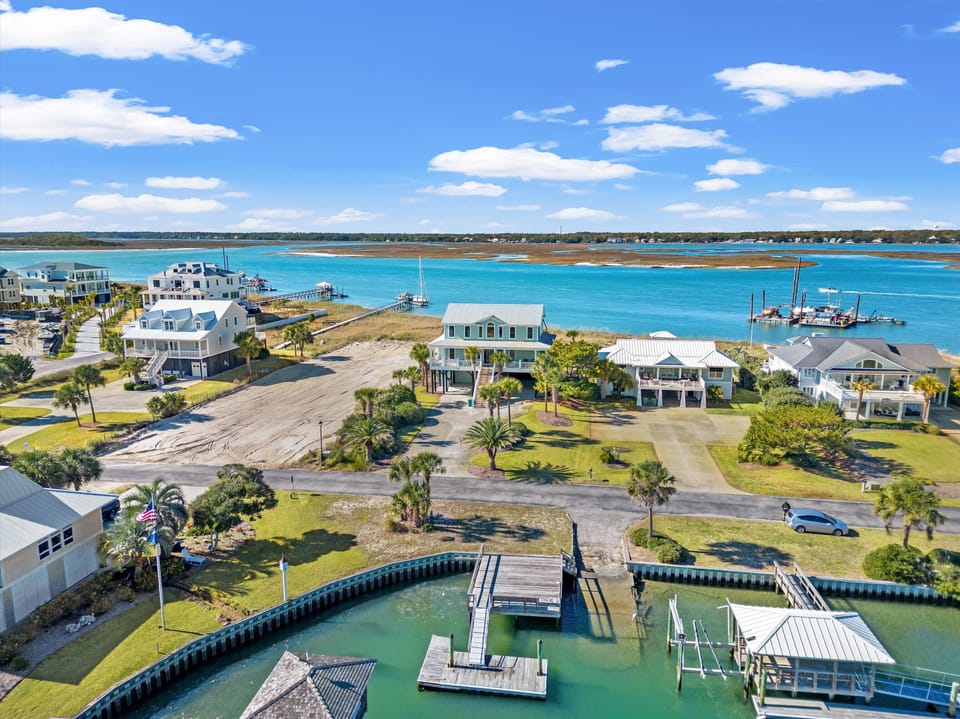 Stunning aerial view showcases waterfront vacation homes along pristine turquoise waters with private docks and boat access.
