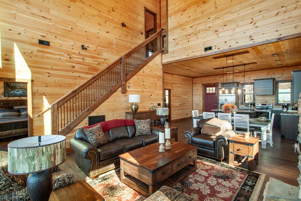 This open-concept cabin features warm wood interiors, inviting furniture, and plenty of natural light.