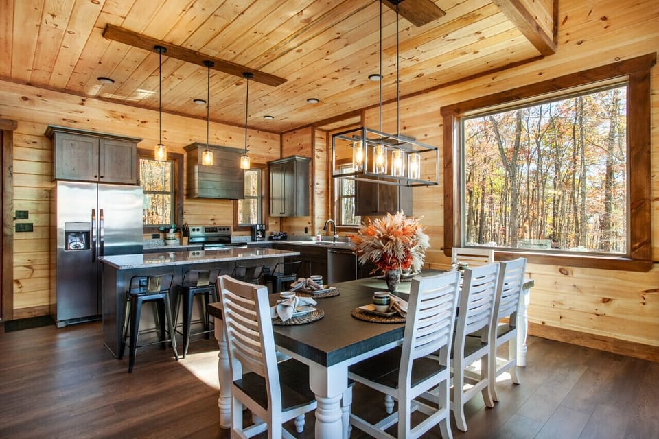 Stylish kitchen and dining area with forest views and warm decor.