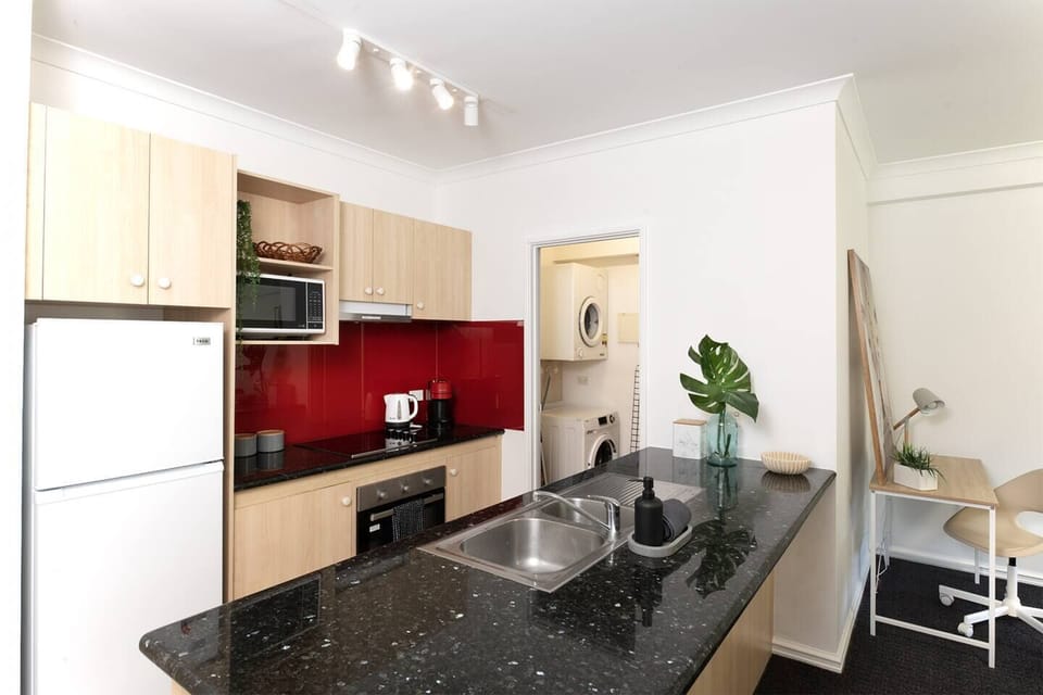 Compact and fully equipped kitchen with a microwave, stove, and a convenient in-unit laundry area.