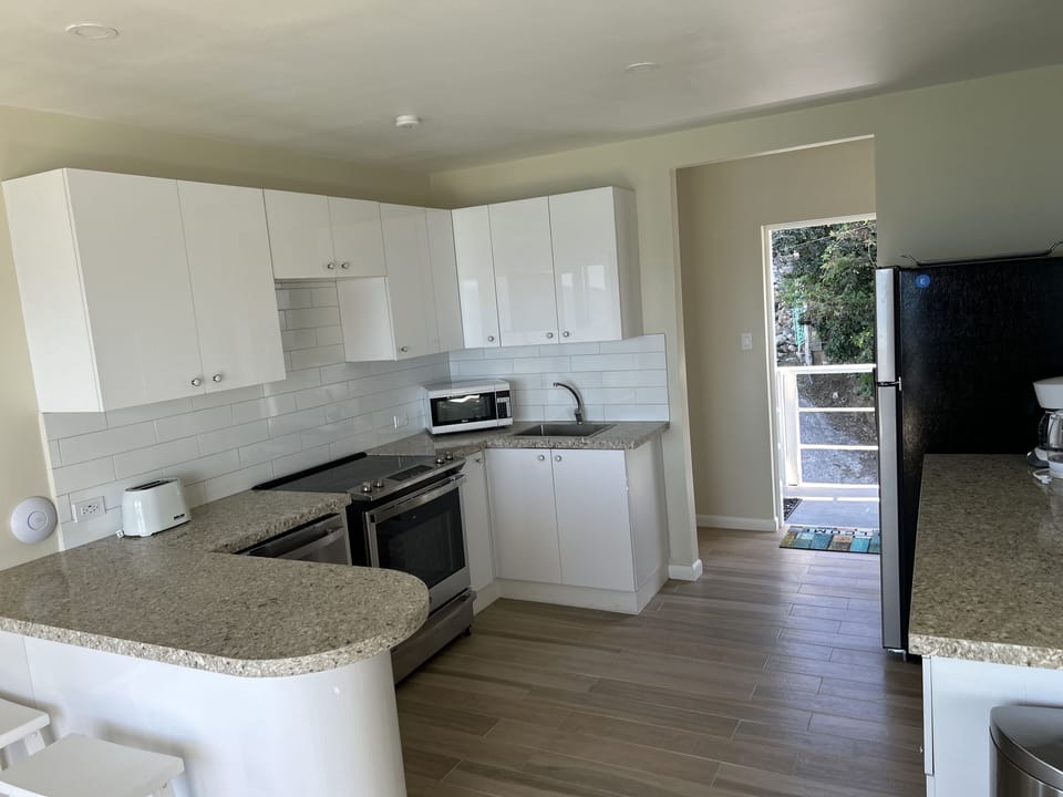 Kitchen with breakfast bar, dishwasher, stove, oven, fridge/freezer, microwave.