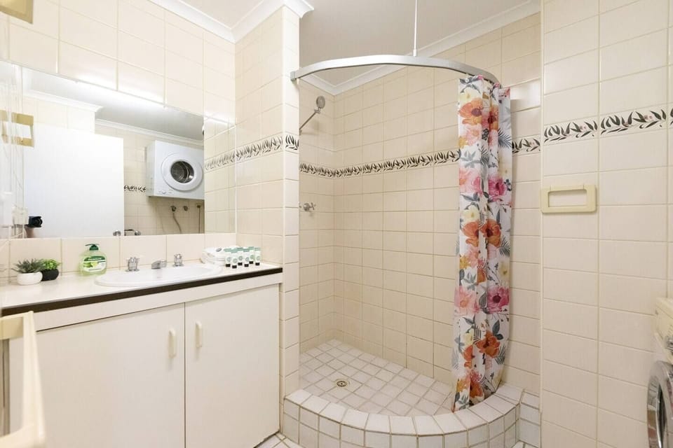 The bathroom features a shower and bathtub, as well as laundry facilities including a washing machine and dryer.