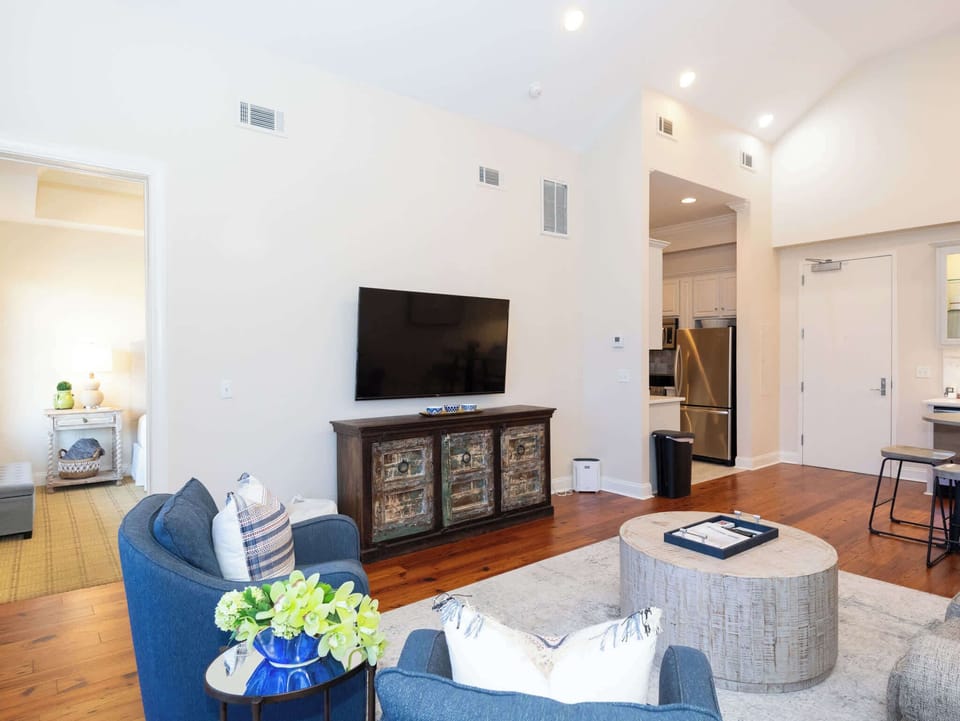 The living room's entertainment wall featuring a large wall-mounted TV above a classic dark wood console.