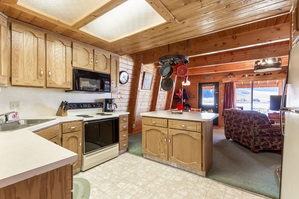 Explore the charming kitchen at Henry's Hatch Cabin, fully equipped for guests' needs, ensuring convenience and comfort during your lakeside getaway.