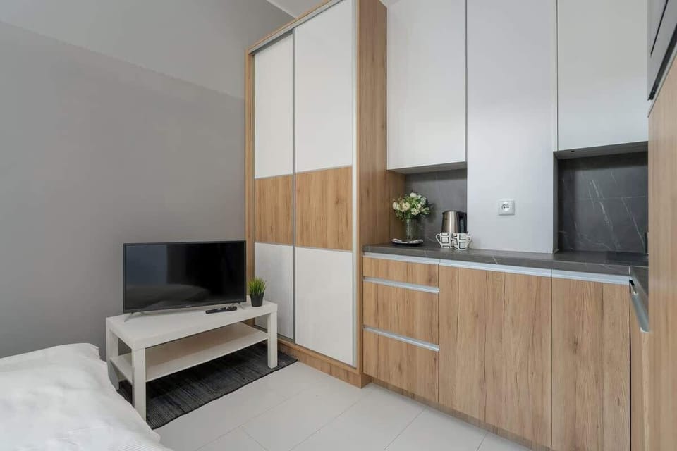 White and wood-toned furniture featuring a wardrobe, cabinets, and a space for a TV.
