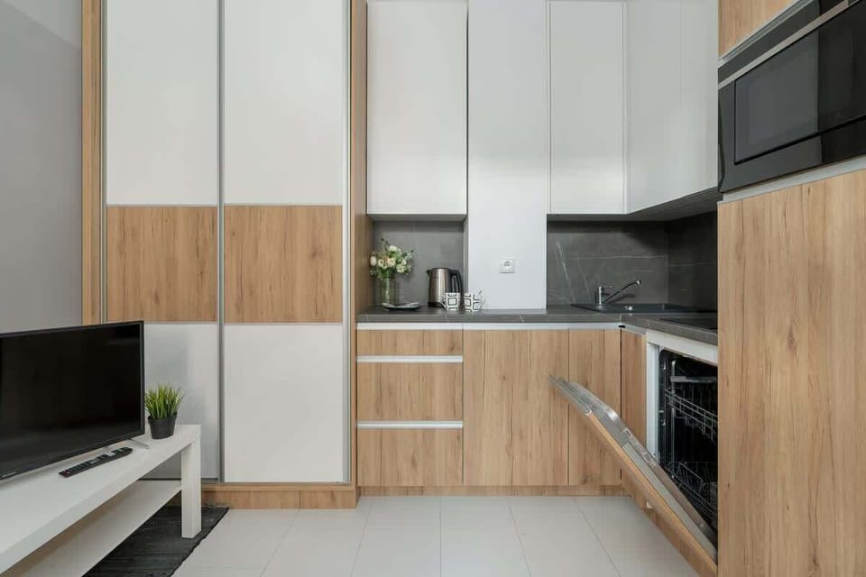 A modern kitchen featuring white cabinetry, wood accents, and a sleek black countertop.
