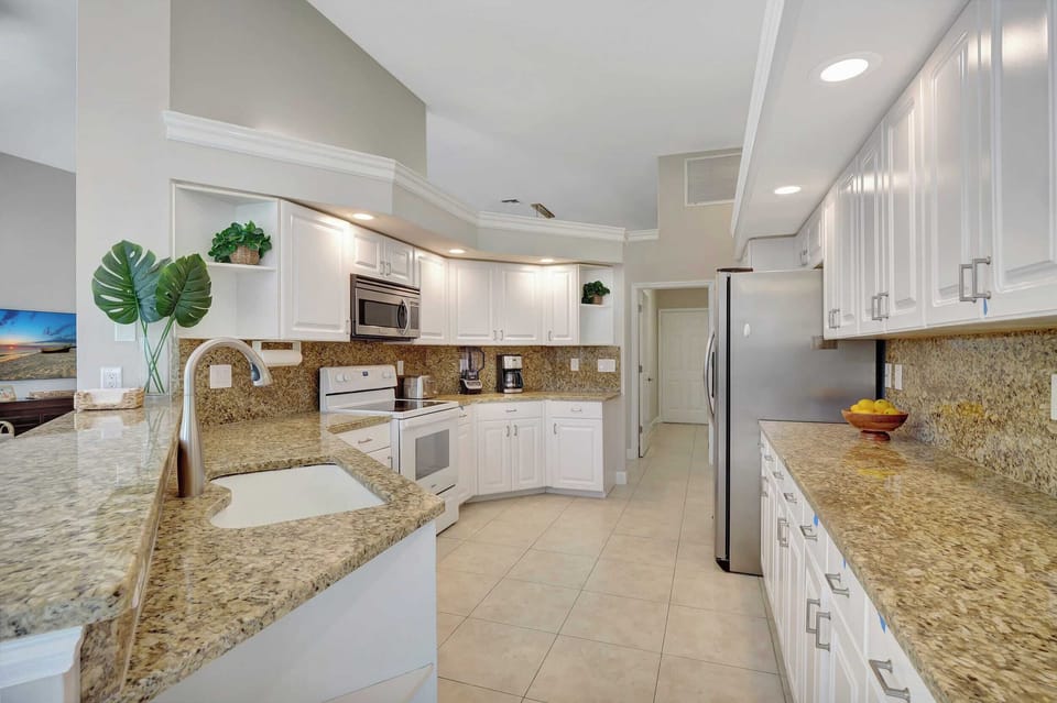 A long view of the kitchen showcasing the granite counters and stainless steel appliances