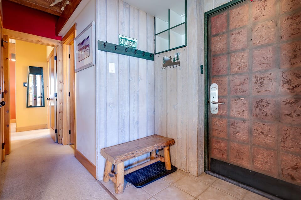 Step into your cozy mountain retreat through this charming entry with rustic wood bench and thoughtful hooks for your gear.