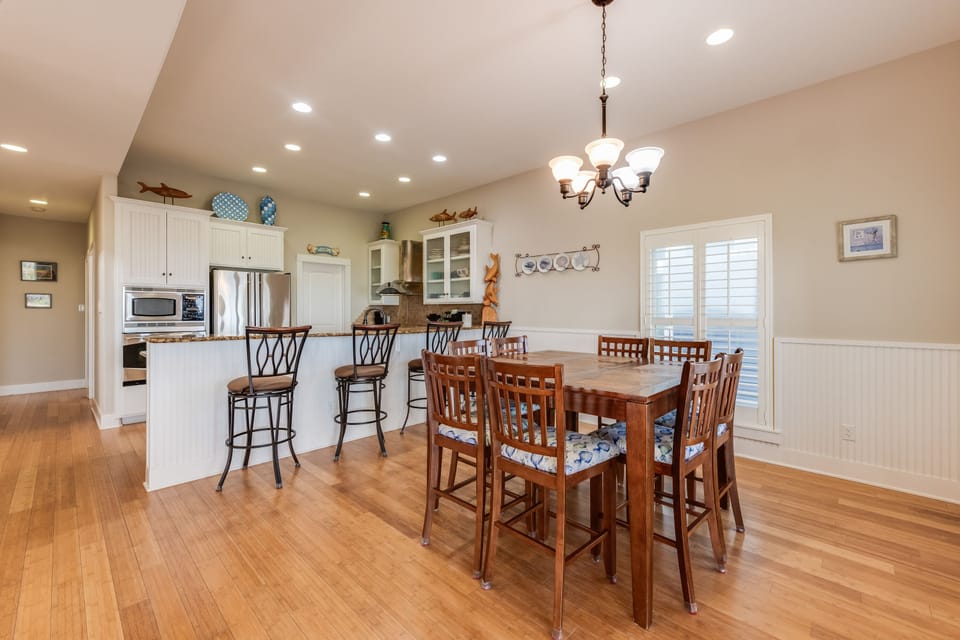 Your open kitchen and dining space features warm wood floors, elegant chandeliers, and a spacious island perfect for cooking together.