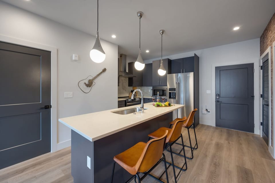 Fully equipped kitchen with stainless steel appliances, basic cooking essentials, toaster, coffee machine, and kitchen island seating.