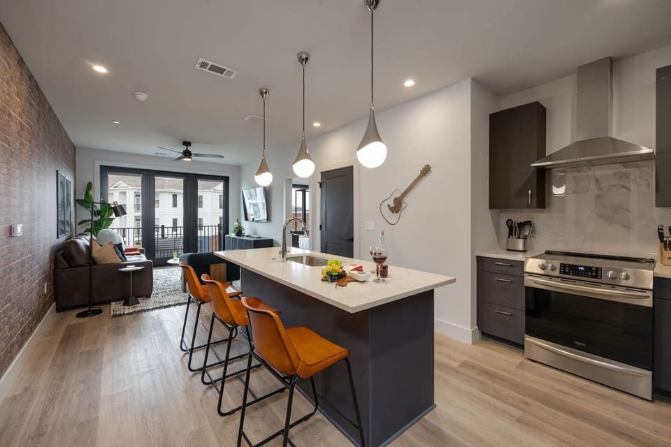 Fully equipped kitchen with stainless steel appliances, basic cooking essentials, toaster, coffee machine, and kitchen island seating.